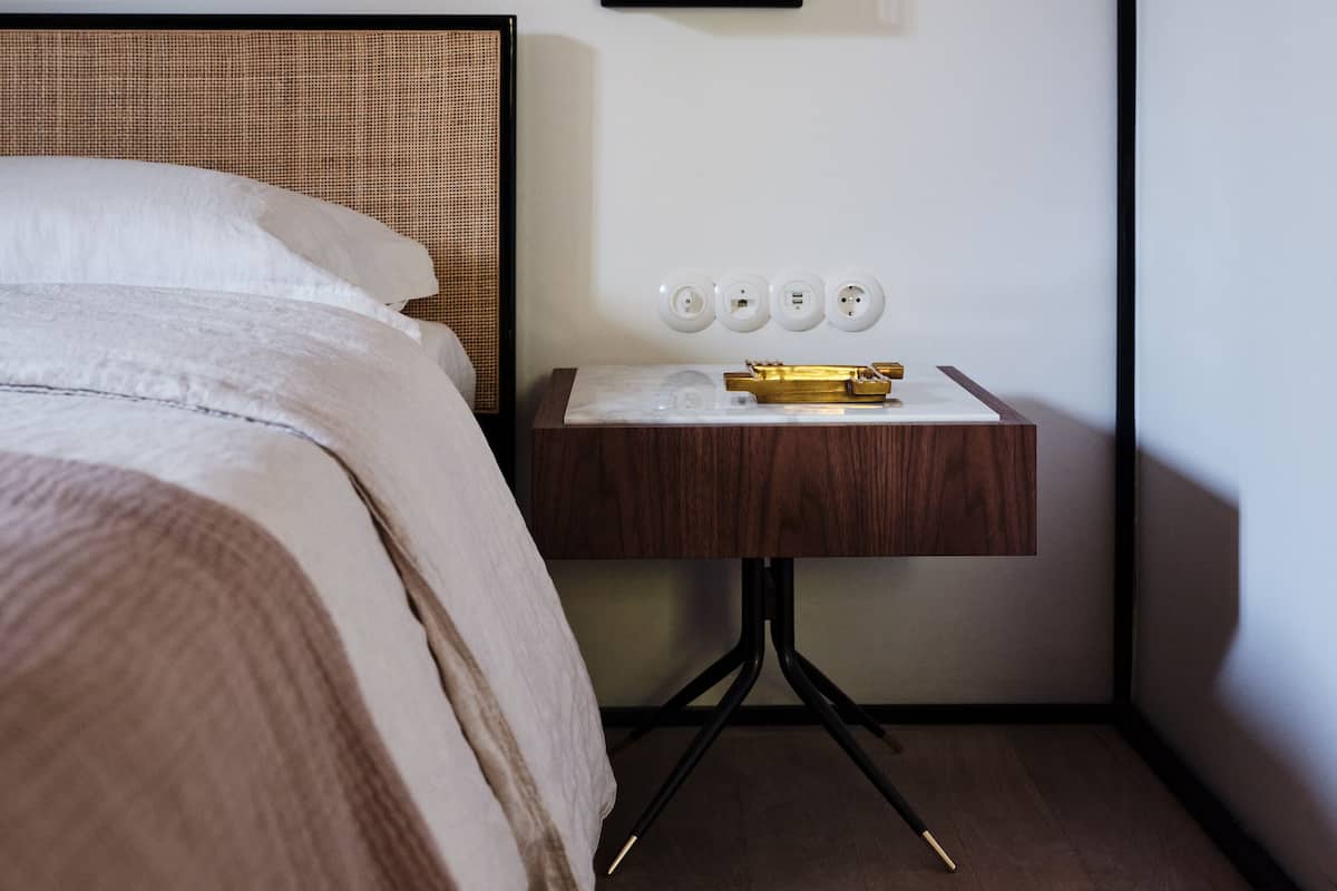 A neatly arranged hotel room with a bed, a bedside table with a lamp, and a framed picture on the wall.