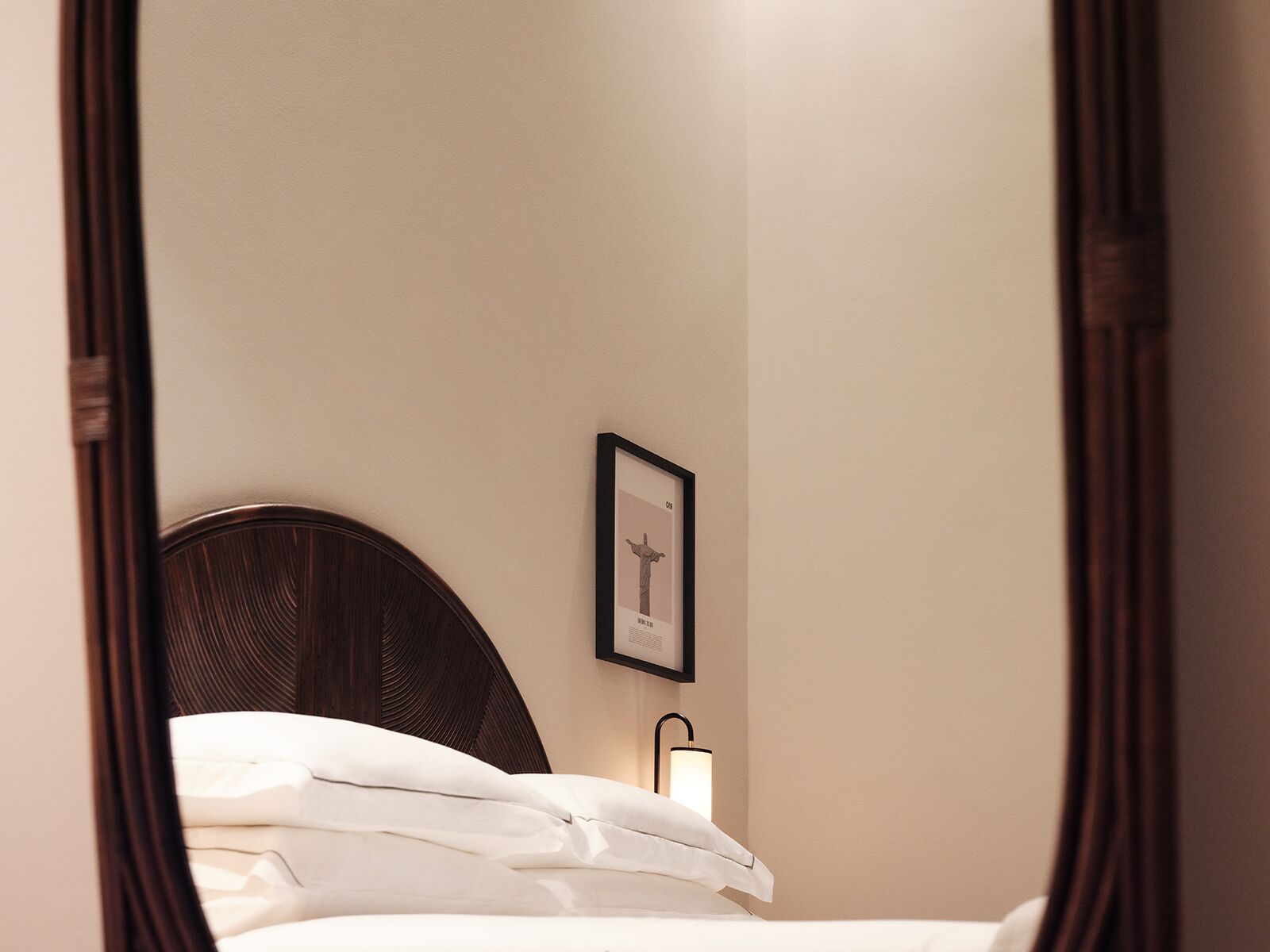 A bedroom with a bed, a framed picture on the wall, and a bedside lamp.