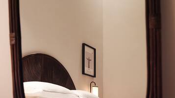 A bedroom with a bed, a framed picture on the wall, and a bedside lamp.
