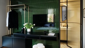 A modern bathroom with a green mosaic wall, a black vanity, a flat-screen TV, and a white towel on the floor. - The Twentyone (Kifisia)