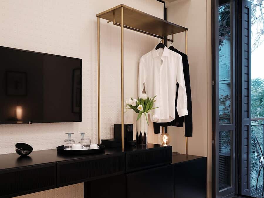 A modern bathroom with a black vanity, a gold-framed mirror, and a white towel hanging on a black hanger.