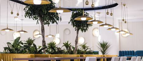 A modern interior with hanging pendant lights, a wooden table, and a yellow sofa.
