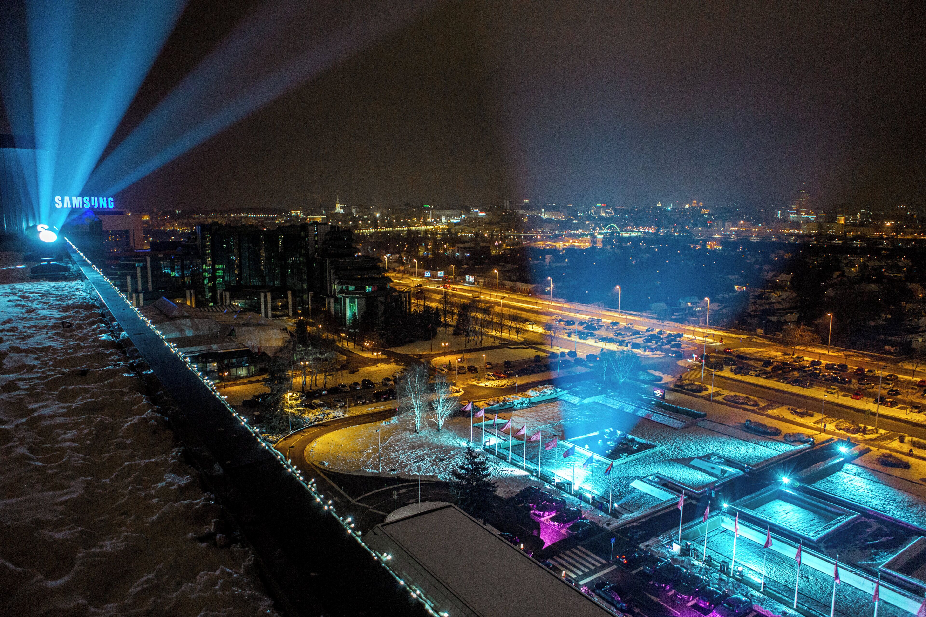 A nighttime cityscape with illuminated buildings and a river.