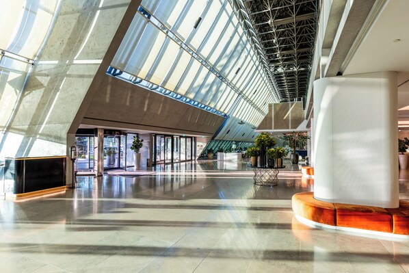 A spacious lobby with a high ceiling, large windows, and a central column. - Crowne Plaza Belgrade by IHG (Belgrade)