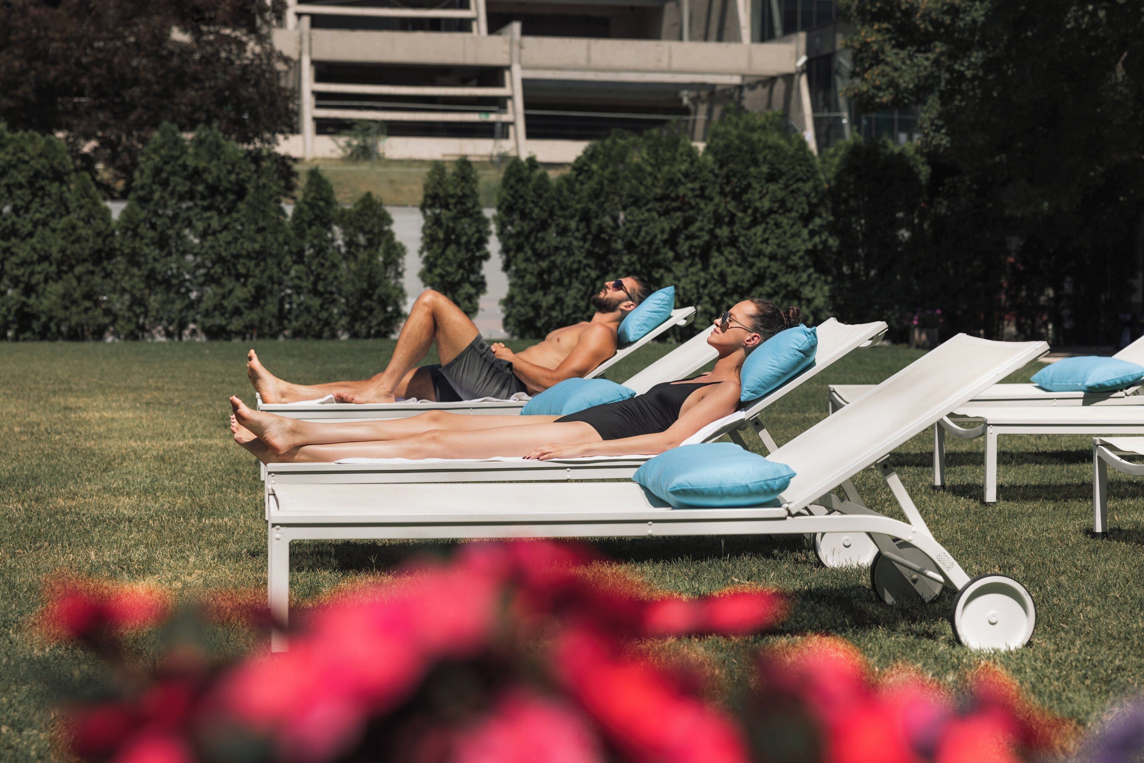 A poolside area with lounge chairs and a building in the background.