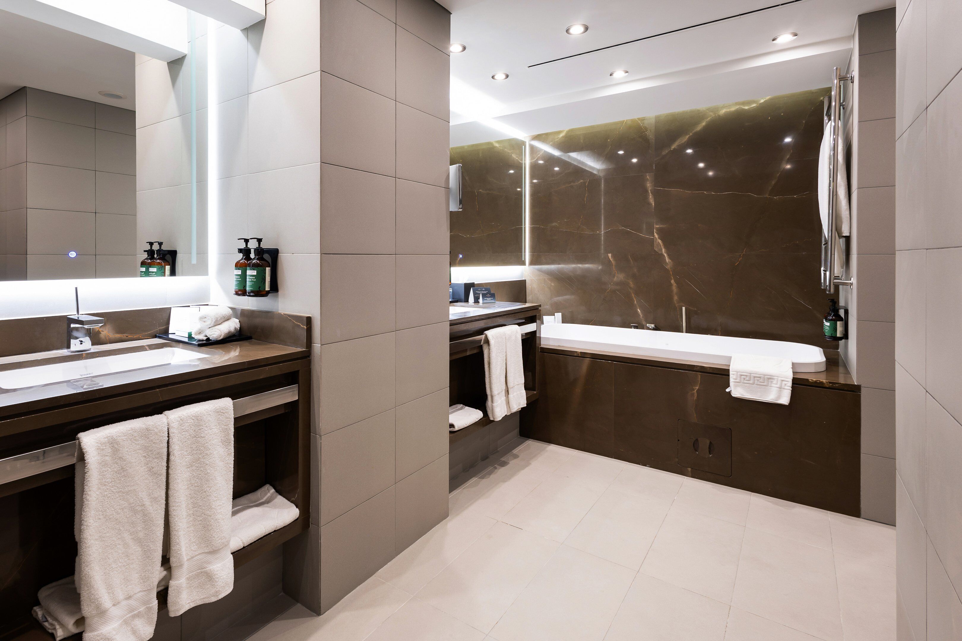 A modern bathroom with a large mirror, a vanity with a sink, and a separate shower area.