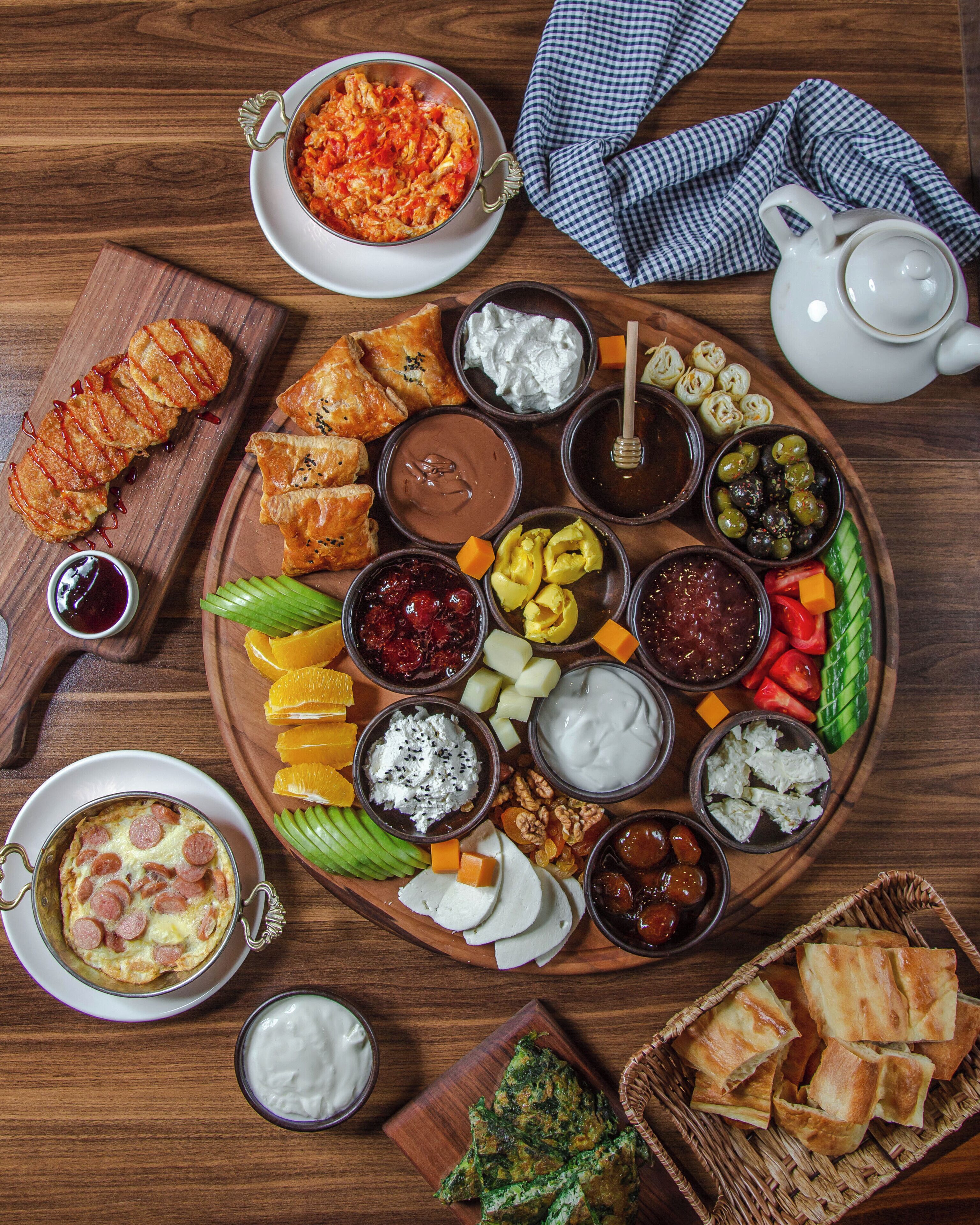 A wooden table with a variety of food items and a teapot.