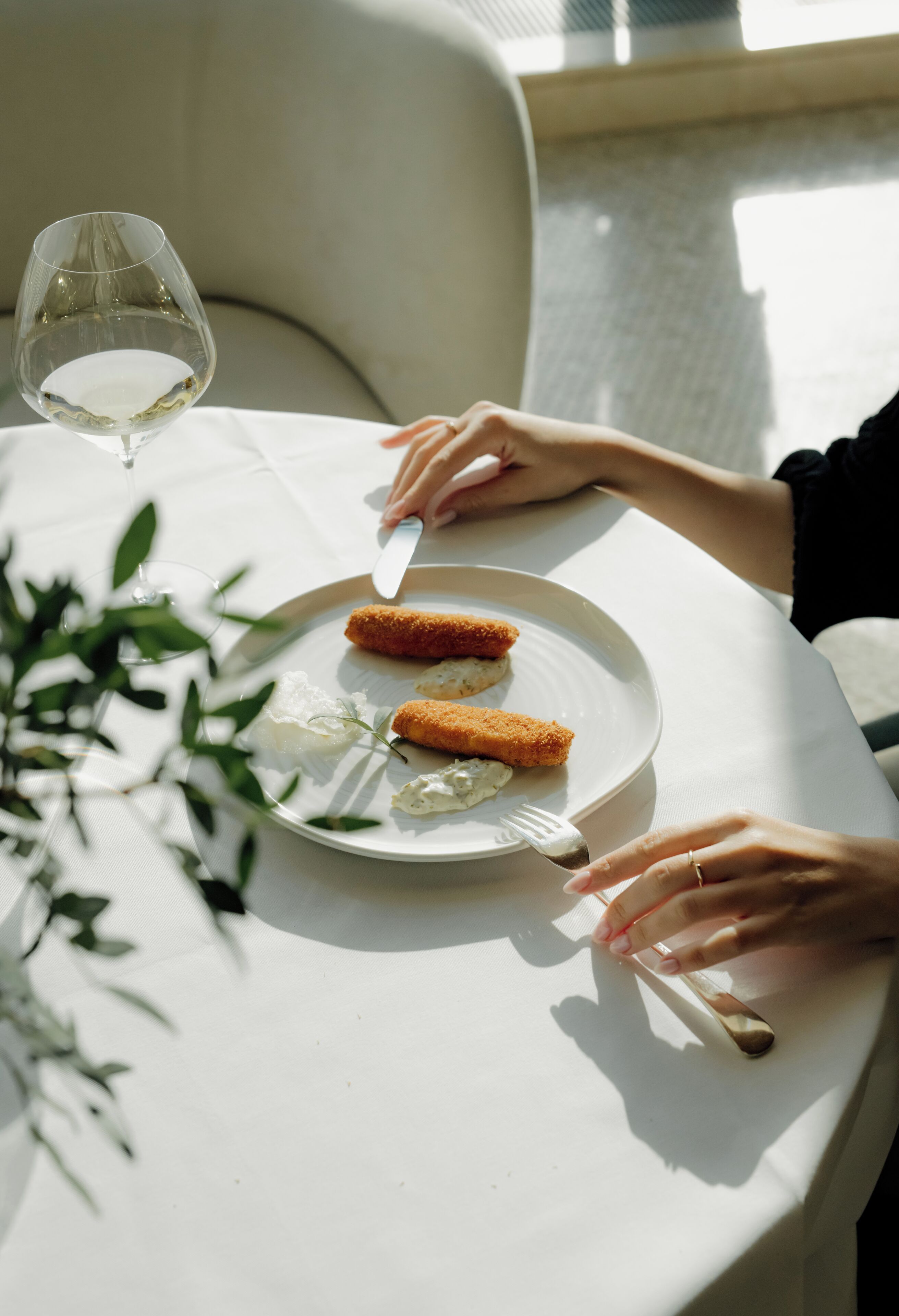 A dining table with a plate of food, a wine glass, and a fork.