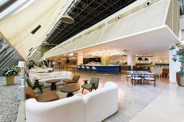 A spacious lobby with a modern design, featuring a bar area, seating arrangements, and a high ceiling with a unique geometric pattern. - Crowne Plaza Belgrade by IHG (Belgrade)