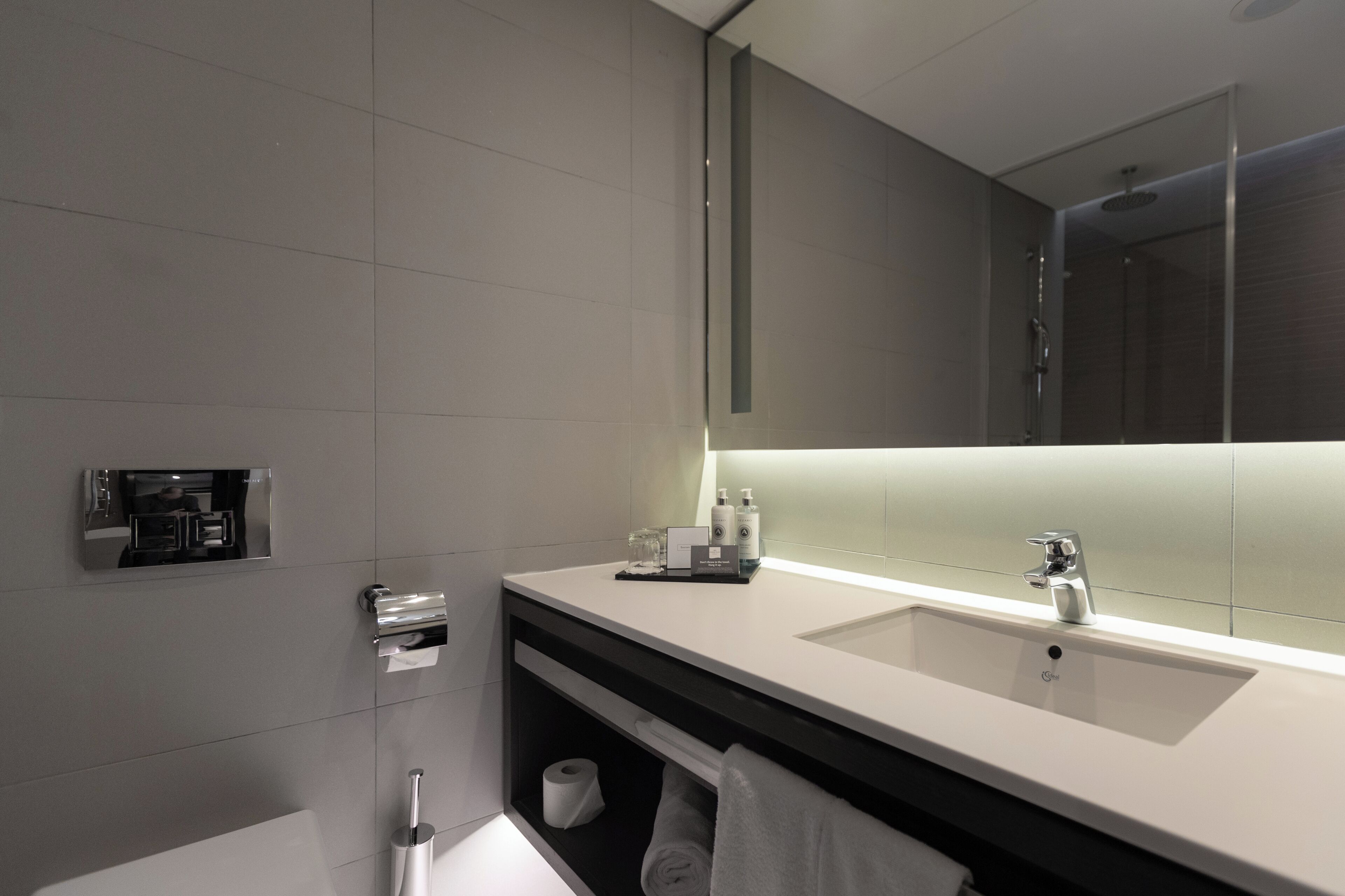 Un baño moderno con dos lavamanos, un espejo grande y una zona de ducha.