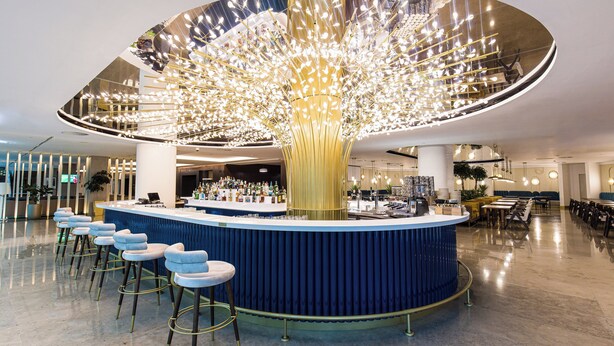 A modern bar area with a unique ceiling design, bar stools, and a seating area with tables and chairs. - Crowne Plaza Belgrade by IHG (Belgrade)