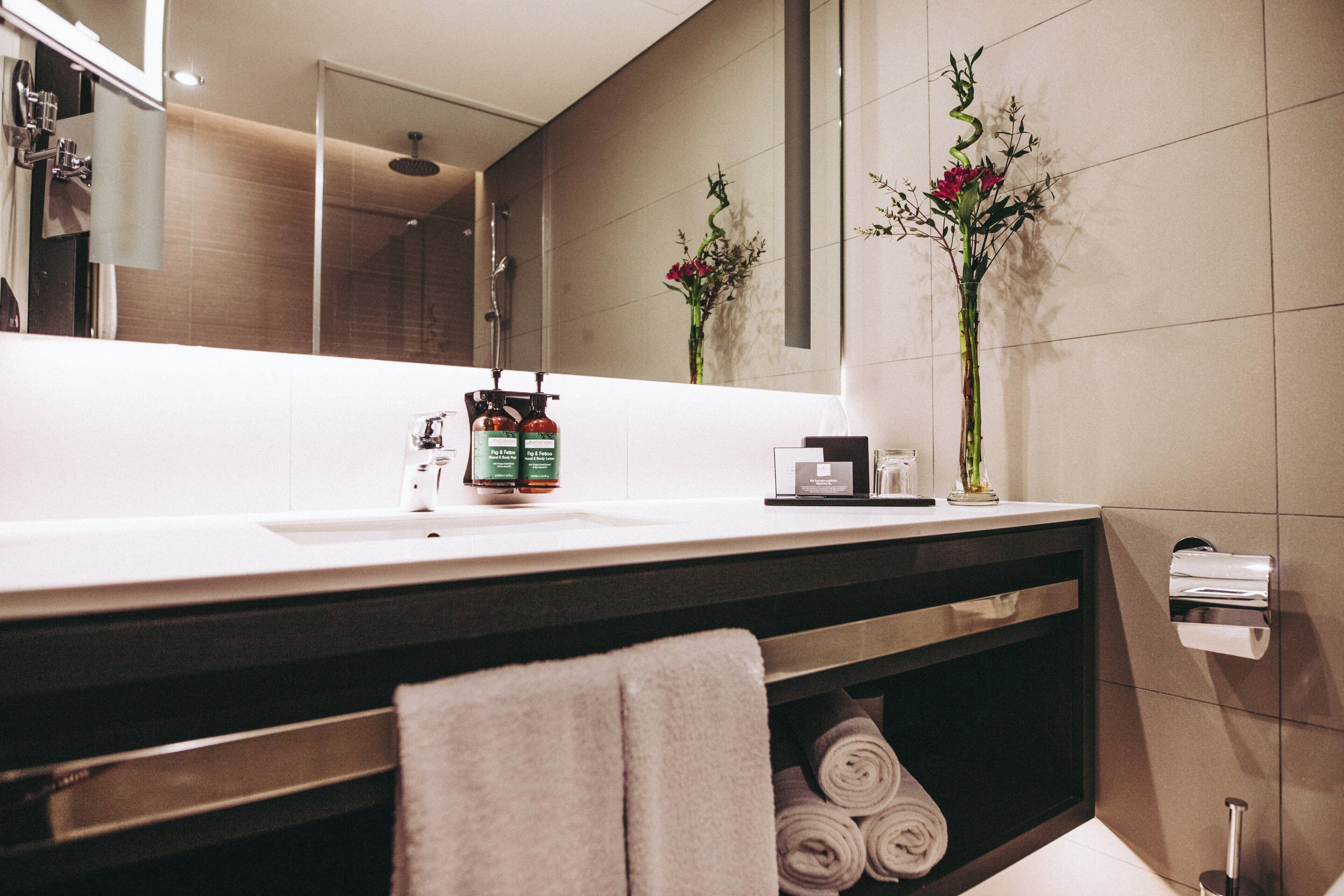 Une salle de bain moderne avec un grand miroir, un lavabo et un porte-serviettes.