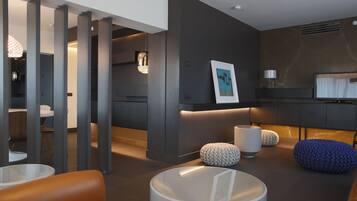 A modern living room with a sofa, ottomans, a round coffee table, and a TV.