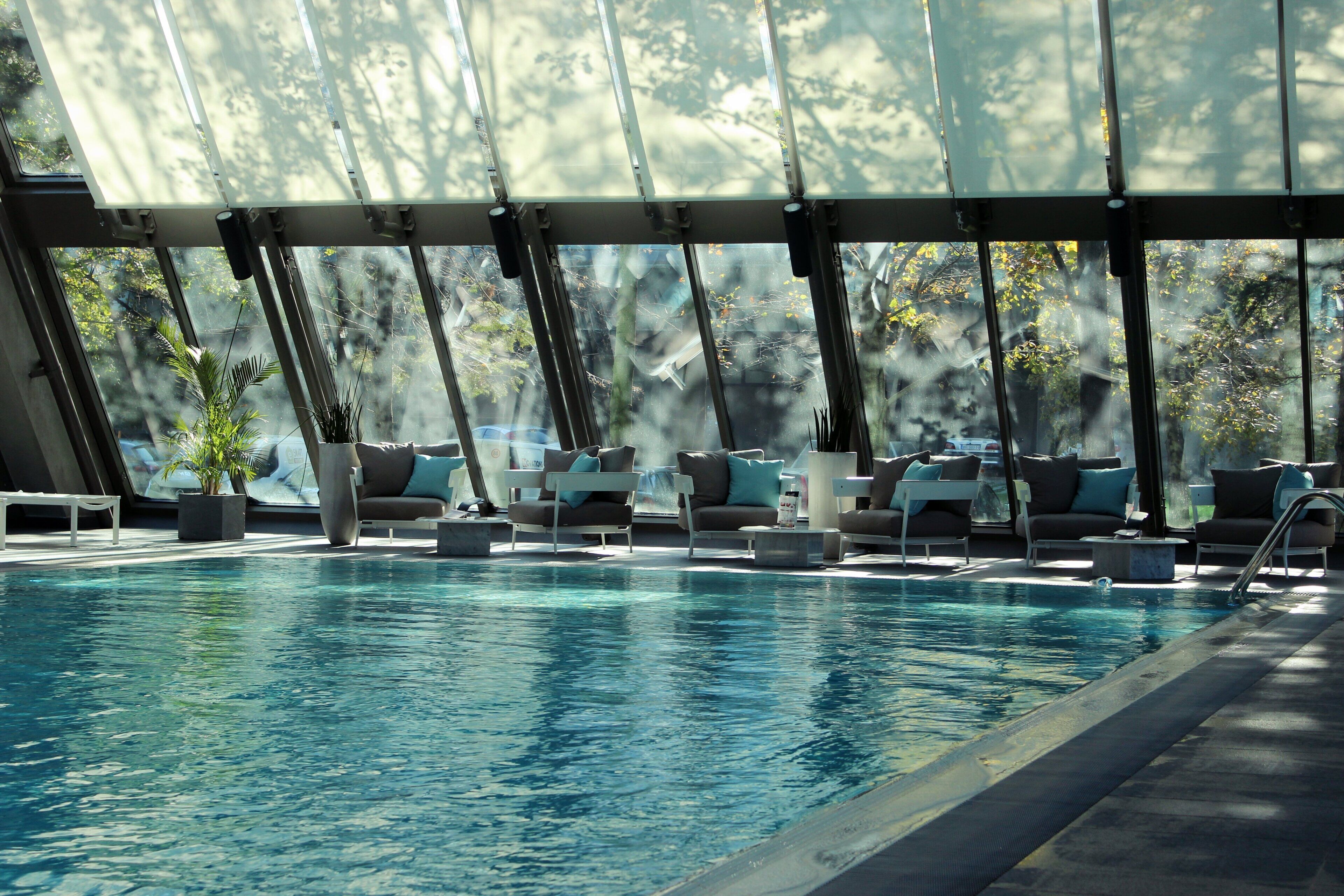 Un área de piscina con sillas de descanso y una estructura de cristal.