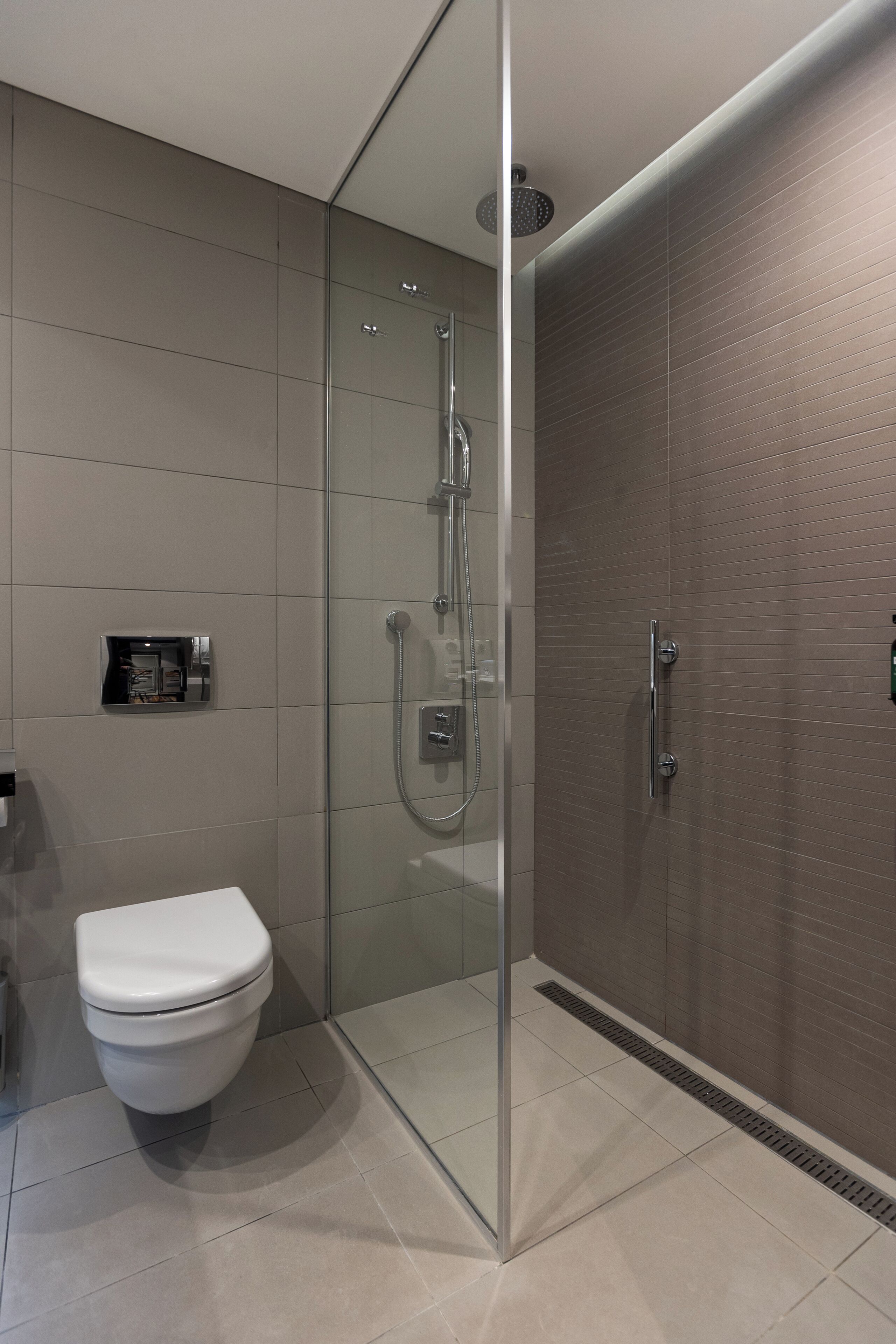A modern bathroom with a glass-enclosed shower, a toilet, and a towel rack.