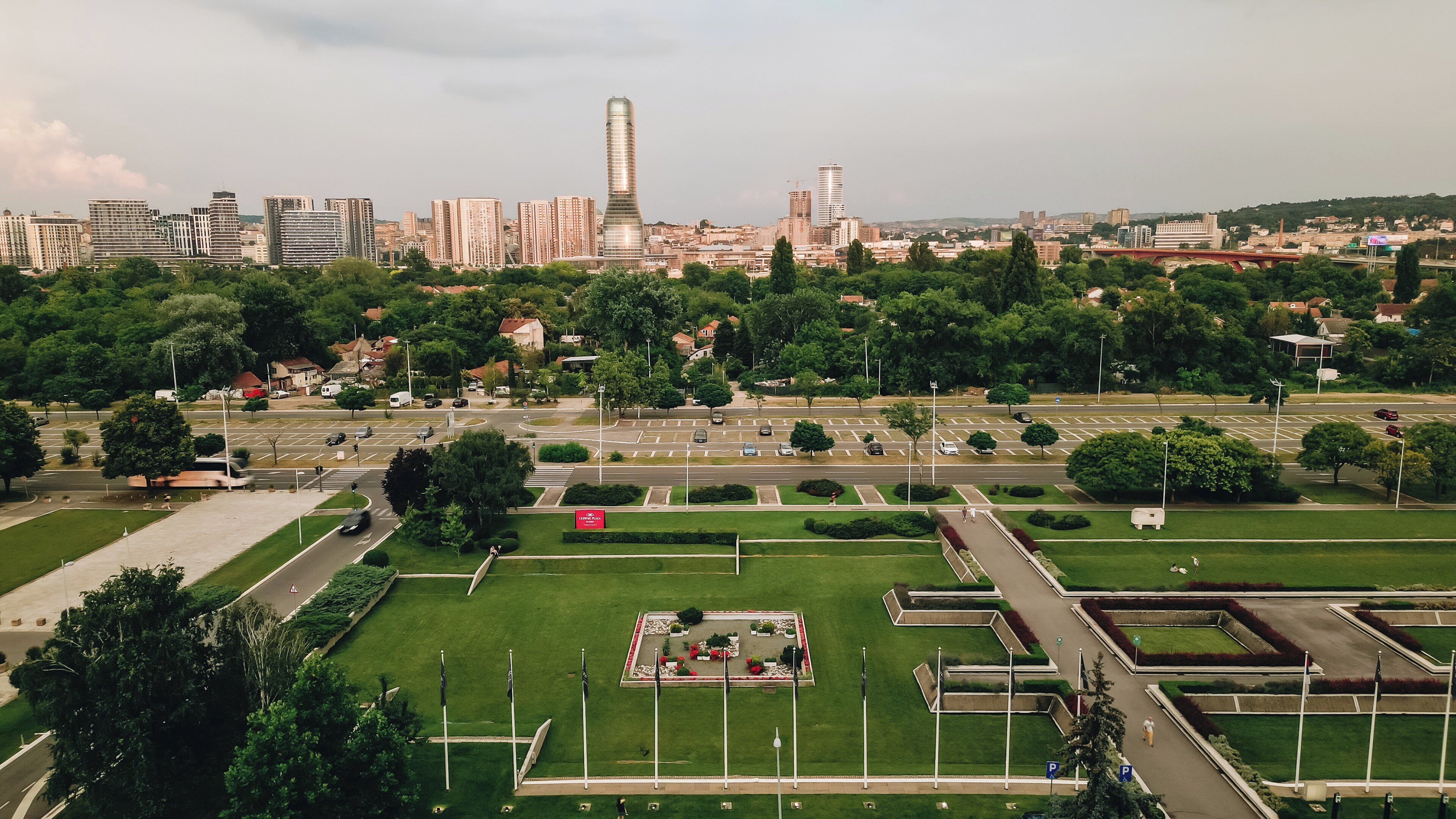 A cityscape with modern buildings, a large green park with a central square, and a prominent tower.