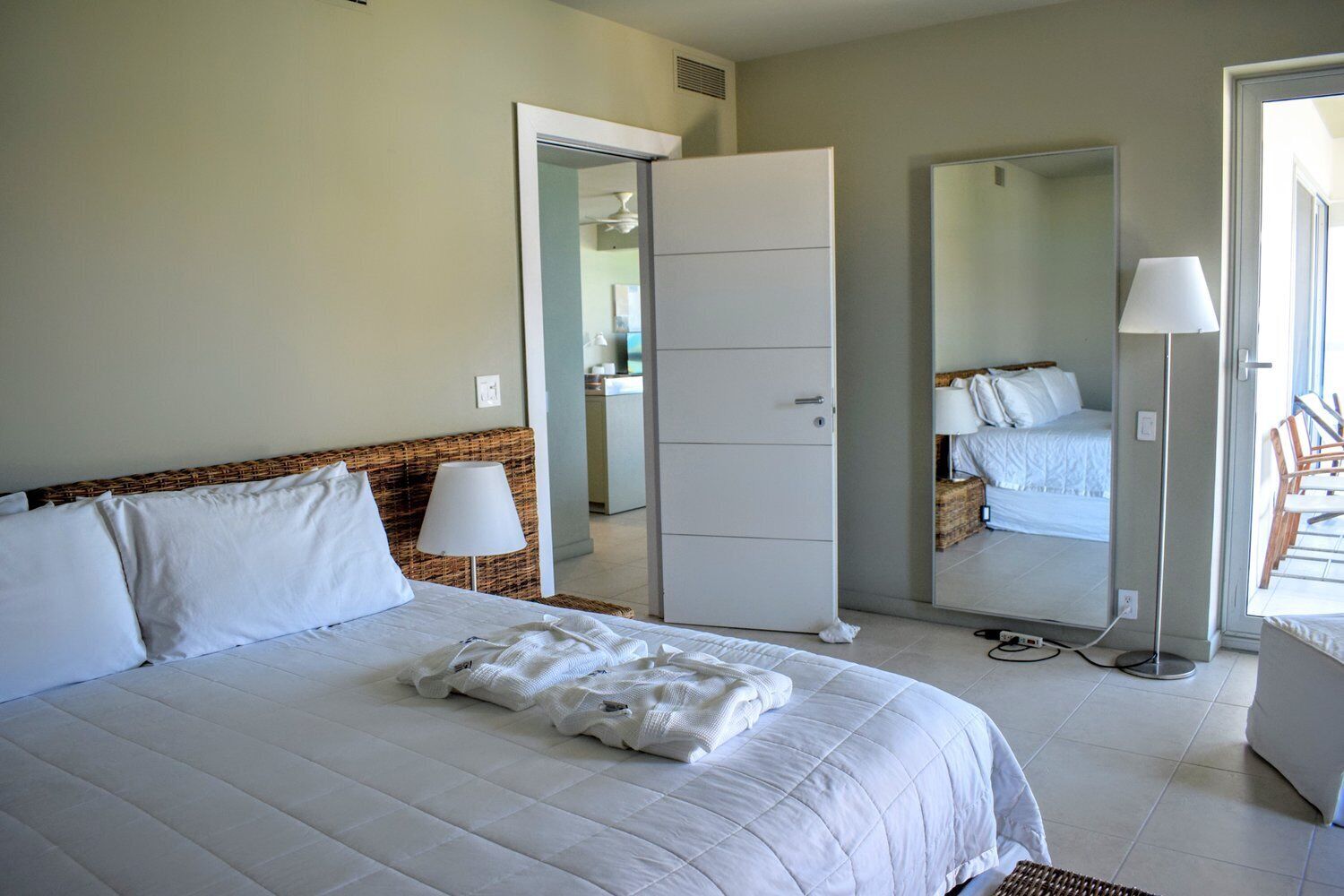 A hotel room with a bed, a wardrobe, a mirror, and a lamp.