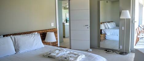A hotel room with a bed, a wardrobe, a mirror, and a lamp.
