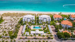An aerial view of a resort with two white buildings, a pool, and a beach. - Le Vele Resort (Providenciales)