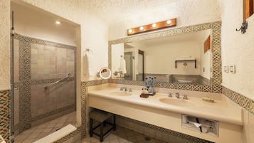 Een badkamer met een inloopdouche, twee wasbakken, een grote spiegel met verlichting en betegeling met een patroon.