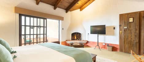 Un dormitorio con una cama grande, chimenea, televisión y techo de madera.