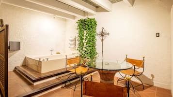 A modern bathroom with a bathtub, a glass table, and chairs.