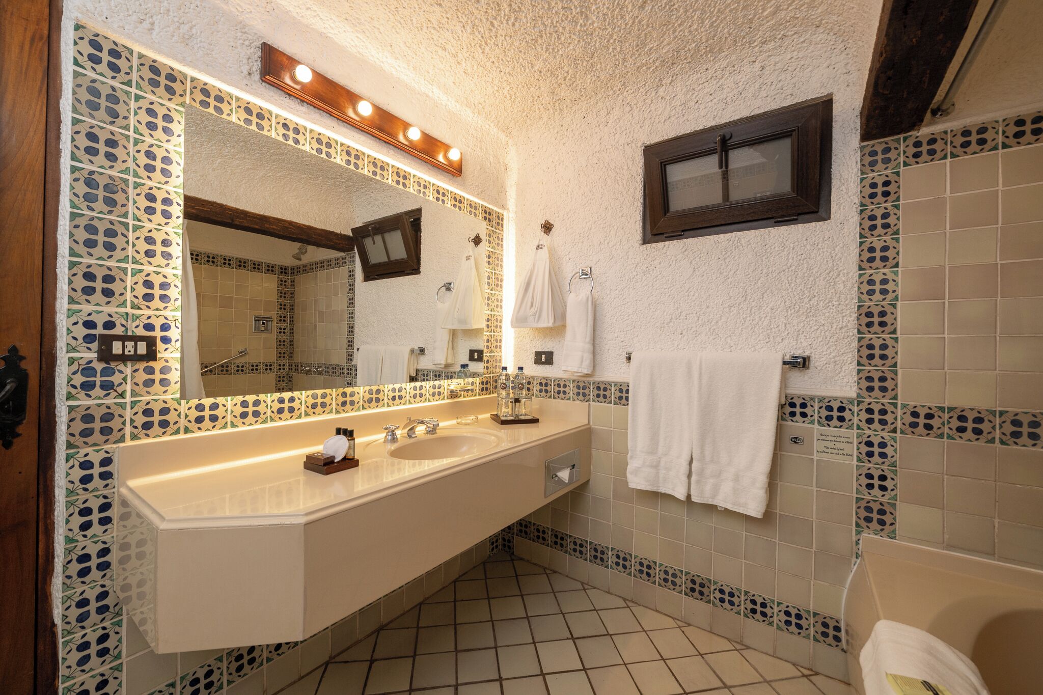 A bathroom with a large mirror, two sinks, and a bathtub.