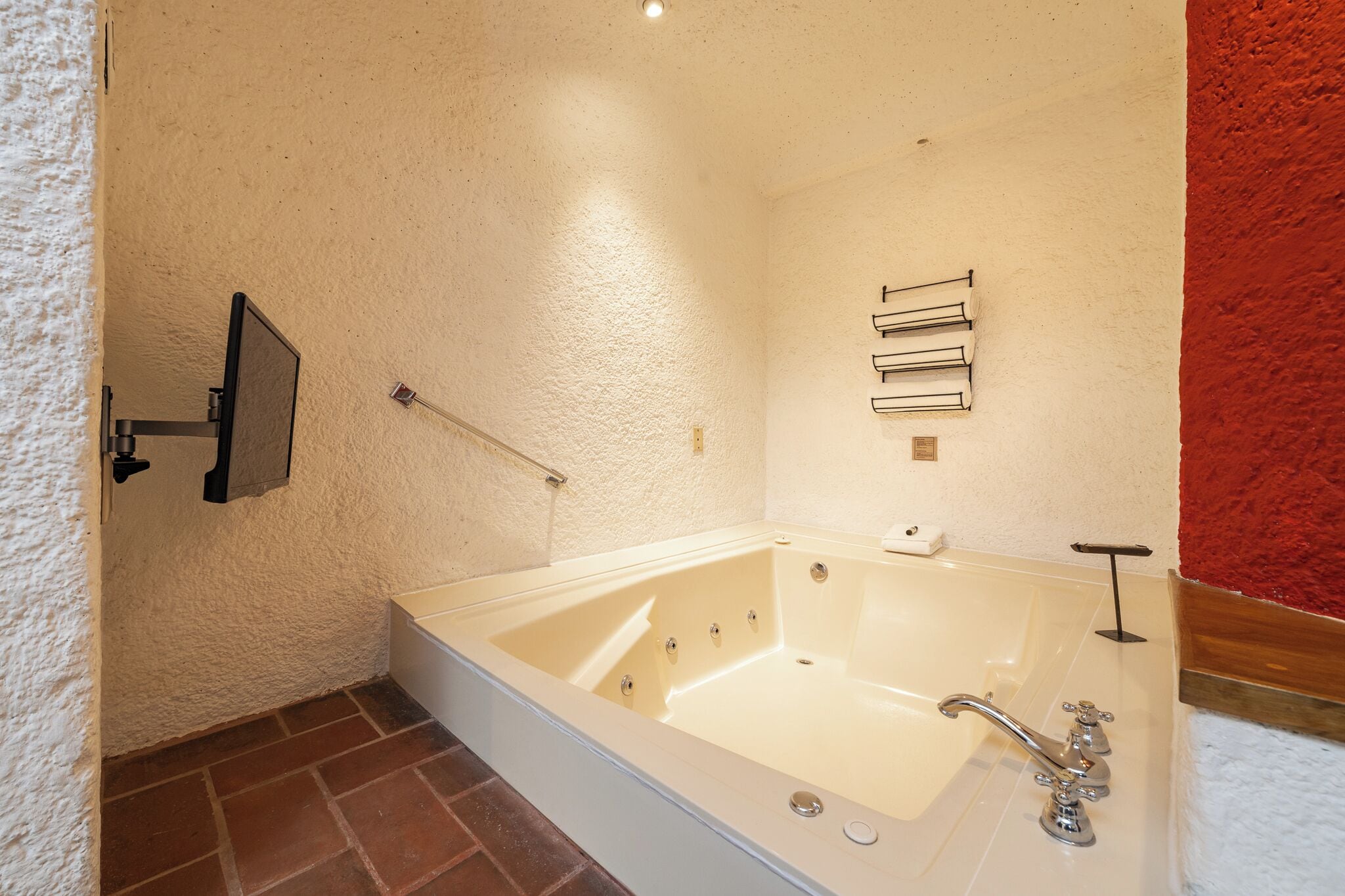 A bathroom with a large bathtub, a towel rack, and a shower control panel.