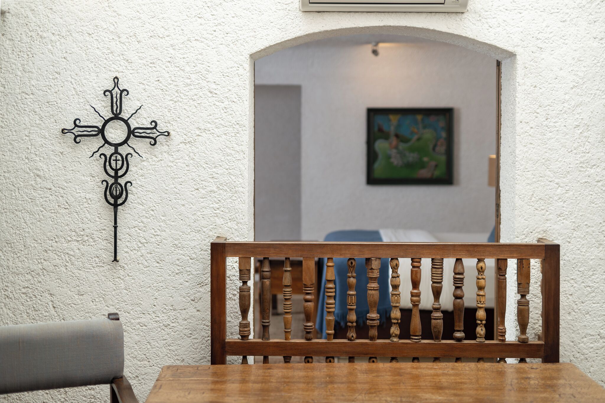 A dining area with a wooden bench, a wall-mounted decorative piece, and a doorway leading to another room.