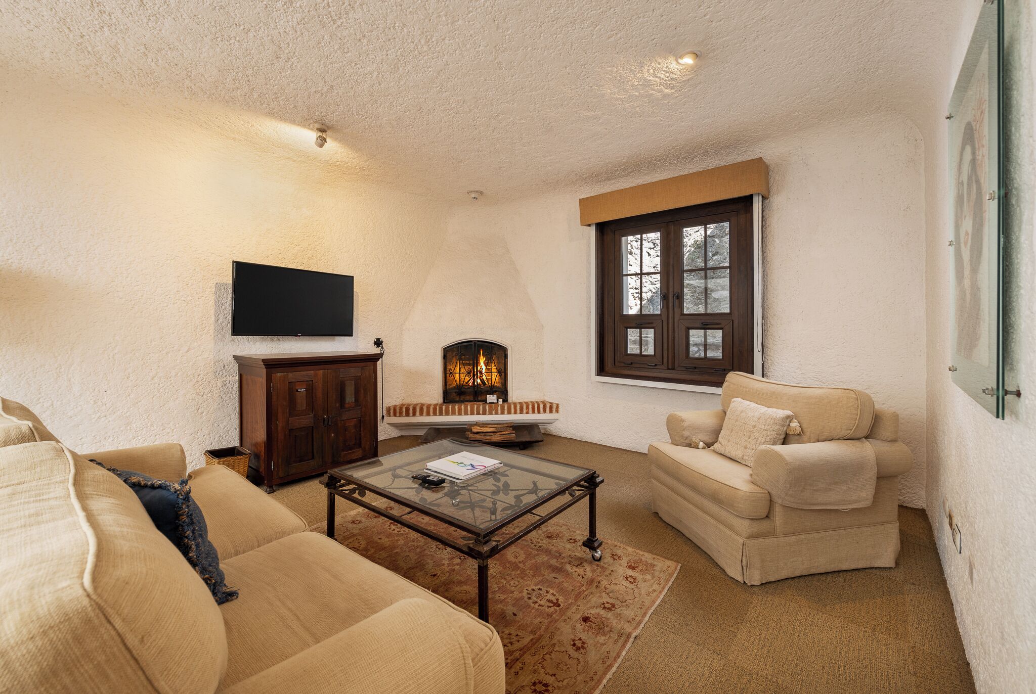 A living room with a fireplace, a television mounted on the wall, and a sofa.