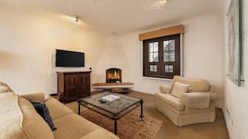 Una sala de estar con chimenea, televisor montado en la pared y un sofá.