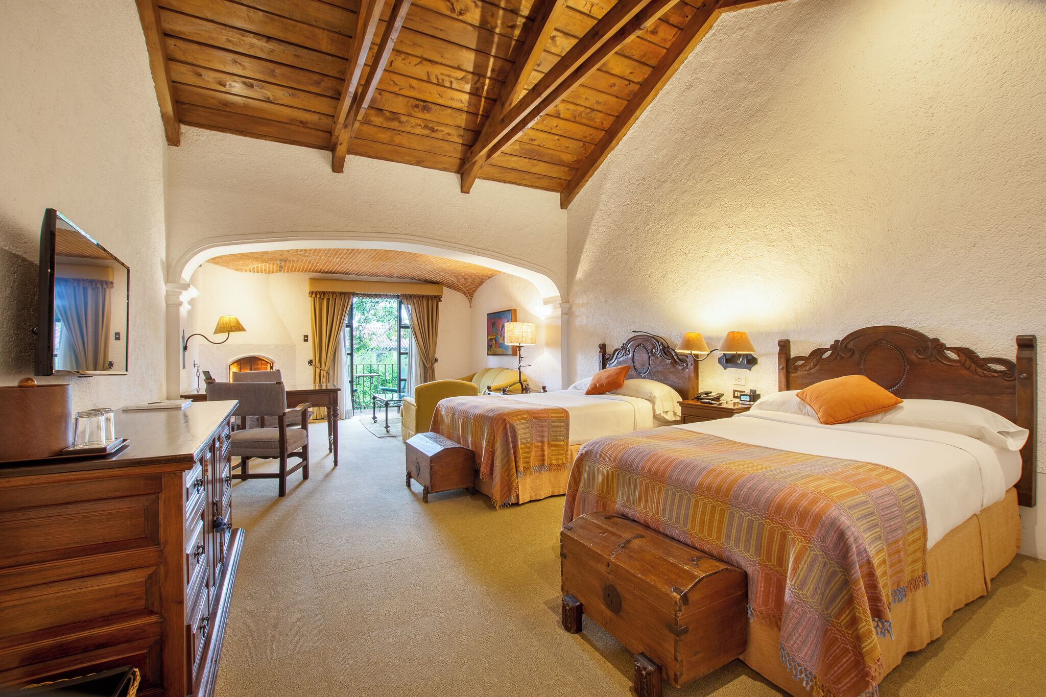 A hotel room with two beds, a desk, a chair, and a television.
