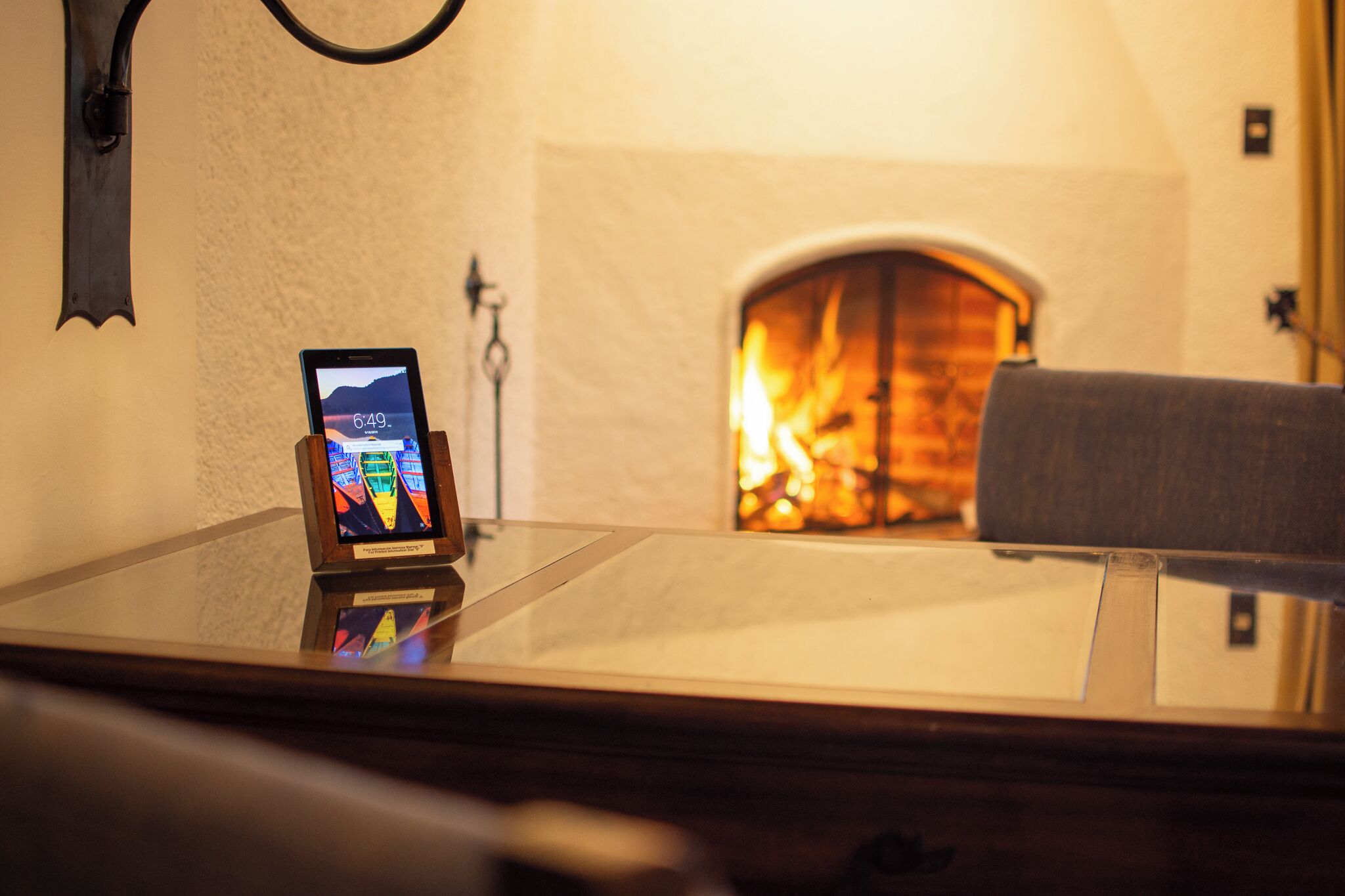 Une pièce avec une cheminée, un téléphone intelligent posé sur un support et un luminaire fixé au mur.
