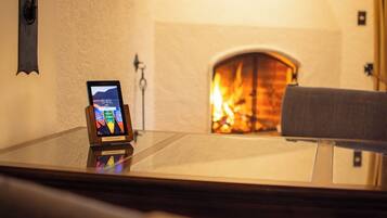 A room with a fireplace, a smartphone on a stand, and a wall-mounted light fixture.
