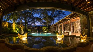 A nighttime view of a pool area with a reflection of trees and a building. - Hotel Museo Spa Casa Santo Domingo (Antigua Guatemala)