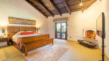A bedroom with a wooden bed, a fireplace, and a door leading to a balcony.