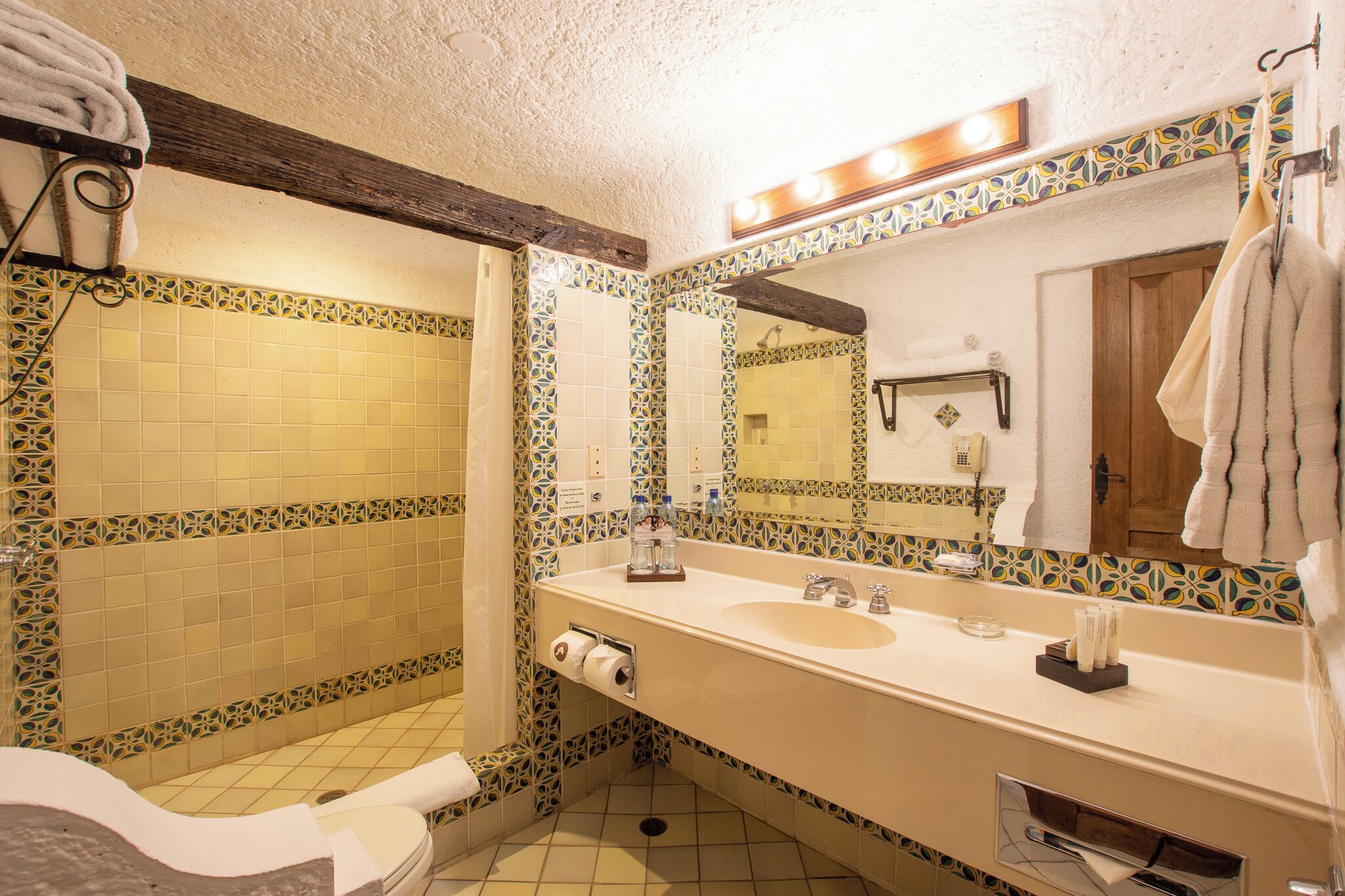 A bathroom with a large mirror, two sinks, and a toilet.