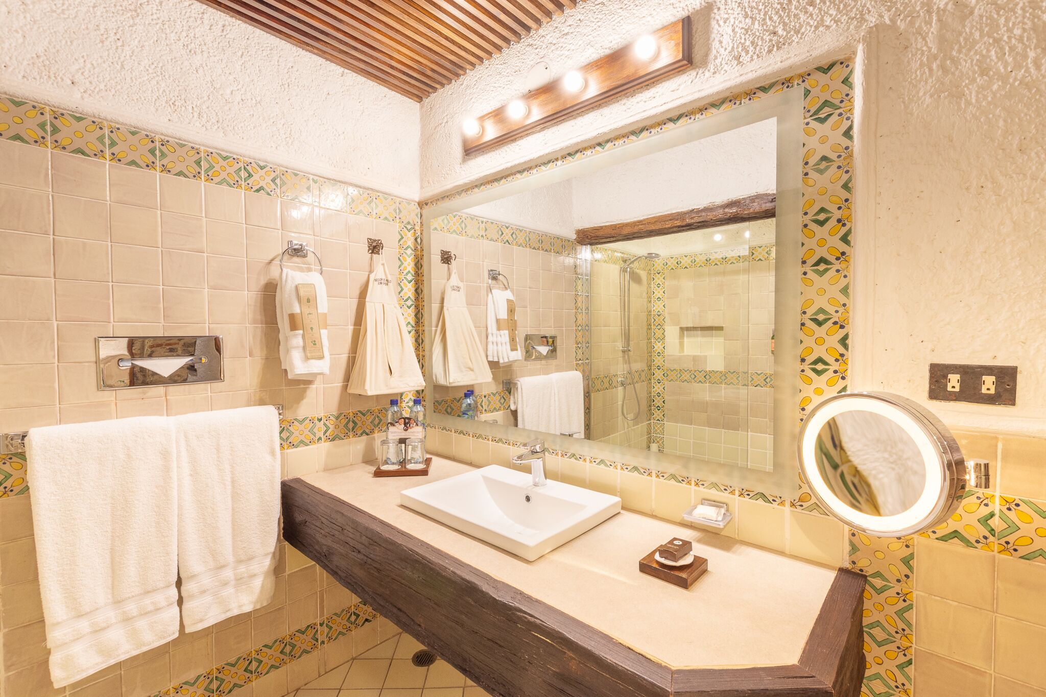 Une salle de bain avec un grand miroir, un lavabo et plusieurs serviettes.