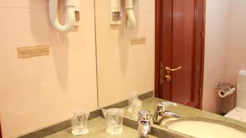 Un baño de hotel con dos lavamanos, un espejo y un secador de manos.