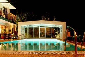 A modern building with a glass facade, a swimming pool, and outdoor seating. - Estalagem Do Vale (São Vicente)