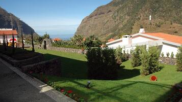 A coastal property with a stone retaining wall, a grassy lawn, and a view of the sea.
