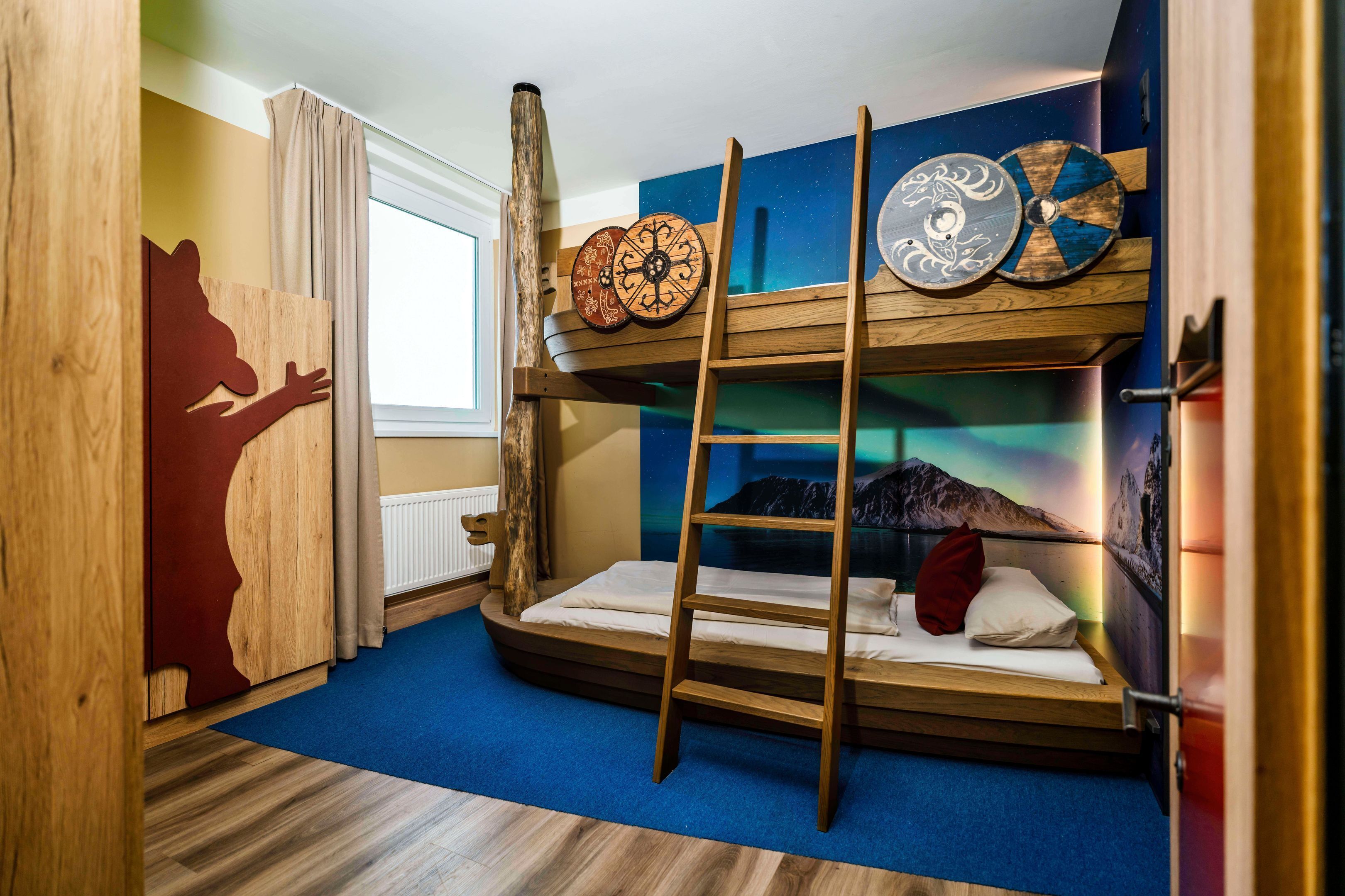 Une chambre avec un lit superposé, une échelle, des éléments de décoration murale en bois et une fenêtre avec des rideaux.