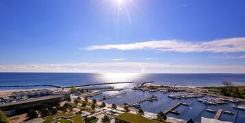 Una marina con barcos amarrados, un muelle que se adentra en el agua, y un edificio de techo plano al frente.