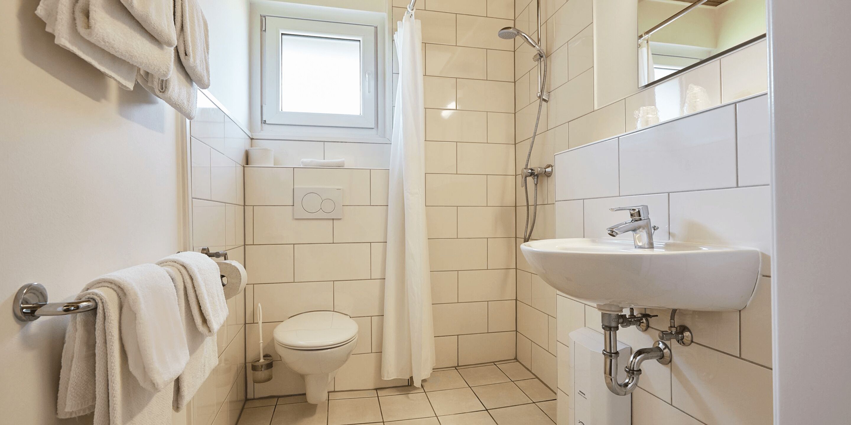 Un baño pequeño y limpio con inodoro, ducha y lavamanos.