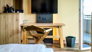 Een moderne kamer met een houten tafel, een aan de muur bevestigde televisie en een schuifdeur naar een balkon.