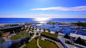 Una marina con imbarcazioni ormeggiate, un molo che si protende sull'acqua e edifici con tetti verdi.