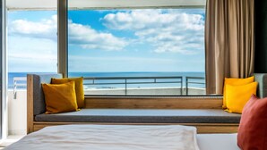 Una stanza con un letto, una seduta finestrino con cuscini e vista sull'oceano.