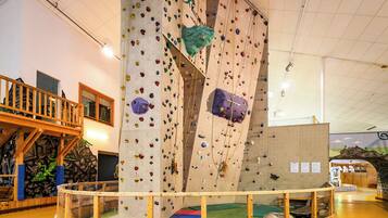 An indoor climbing wall with various holds and a wooden viewing platform.