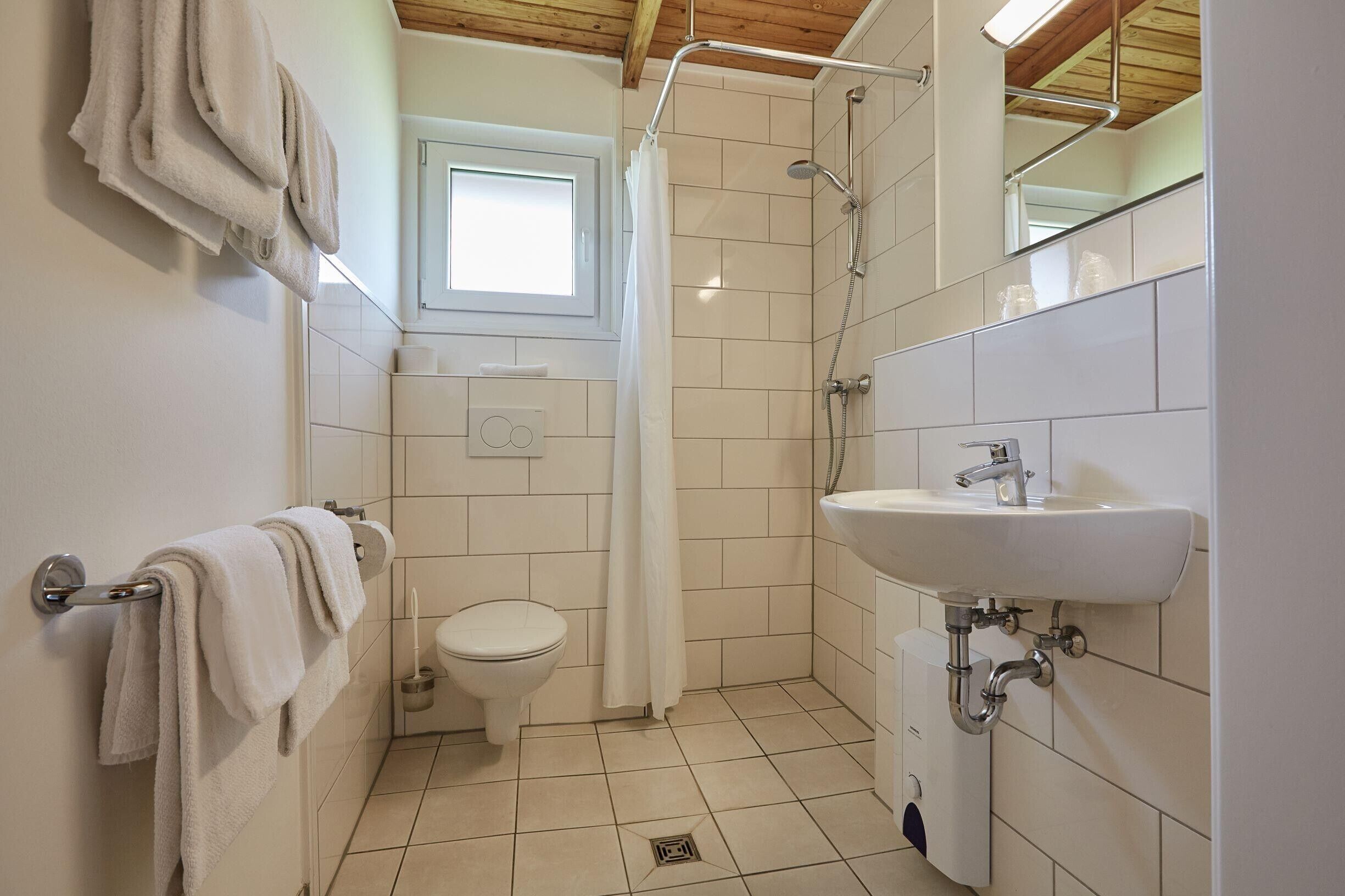 A bathroom with a toilet, shower, and sink.
