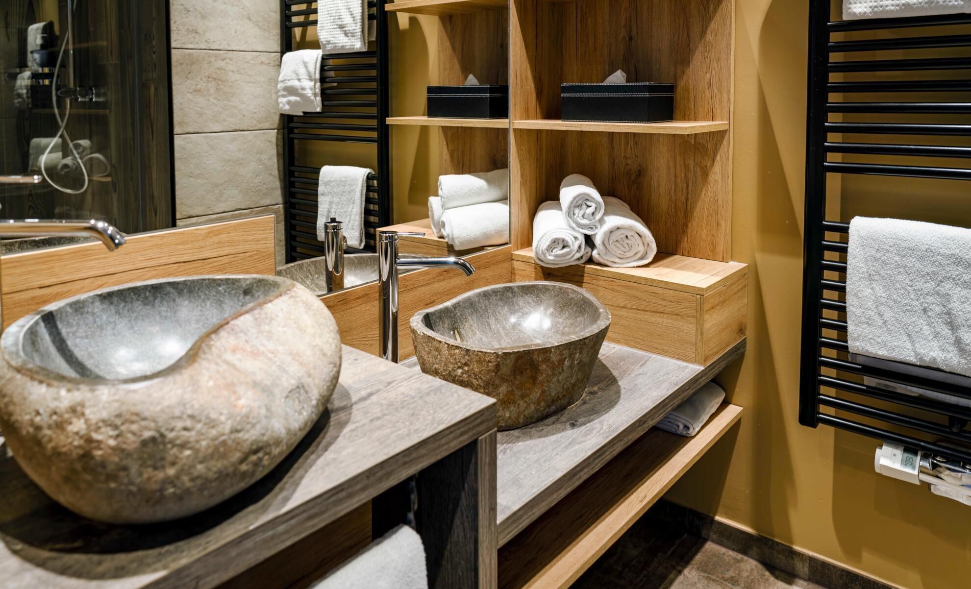 A bathroom with a large stone sink, wooden vanity, and a towel rack with neatly folded towels.